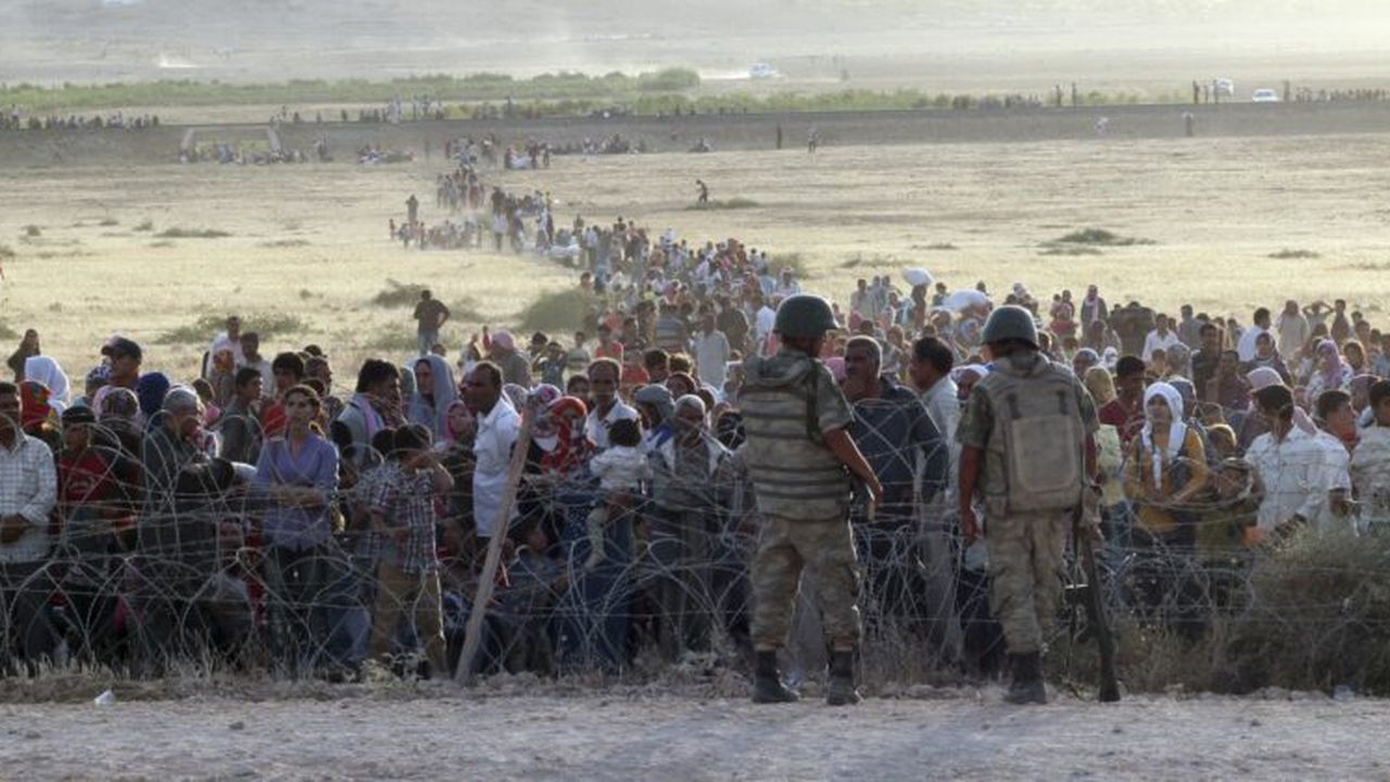 turkish_soldiers_stand_guard_syrian_refugees_wait_behind_border_fences_12382300