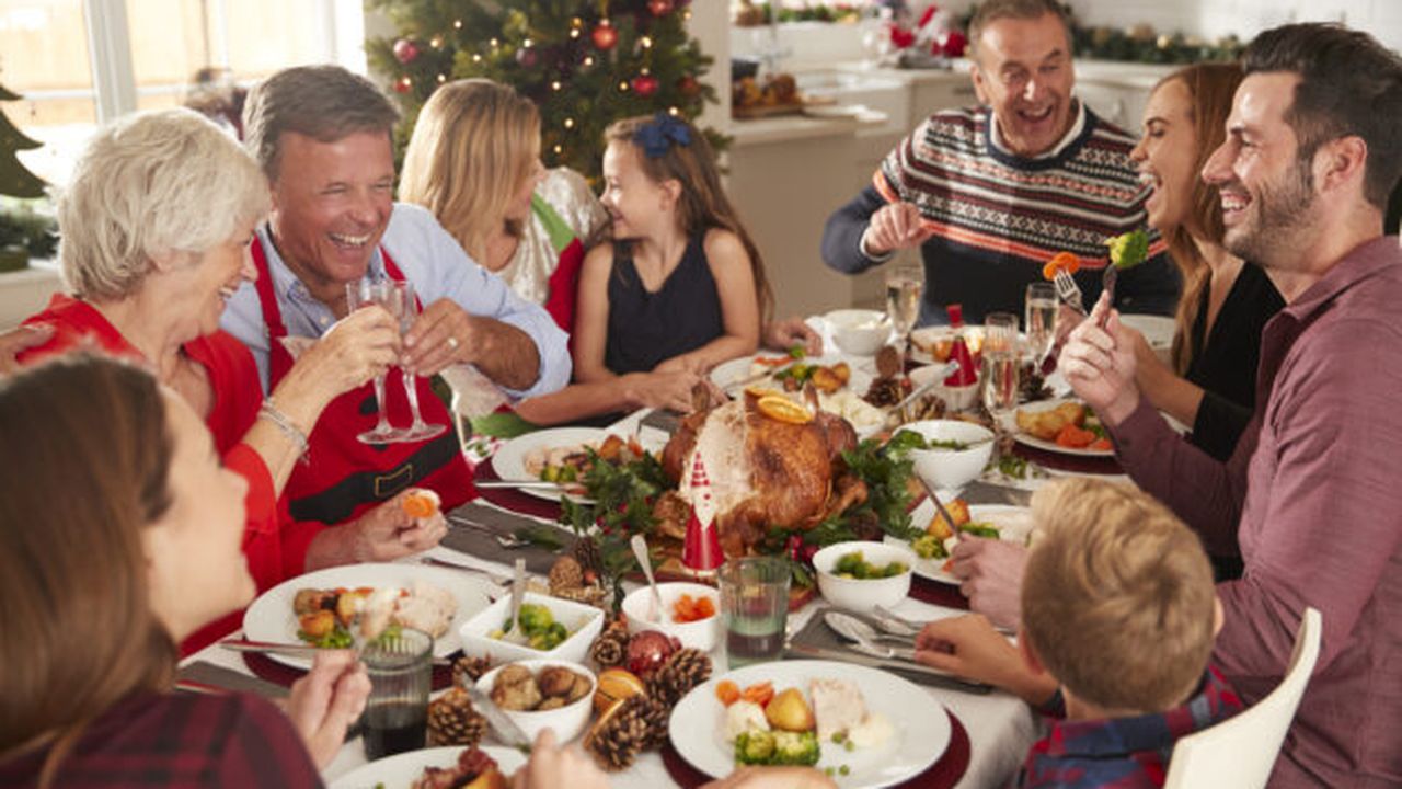 Multi-Generation Family Sitting At Table Enjoying Christmas Meal At Home Together