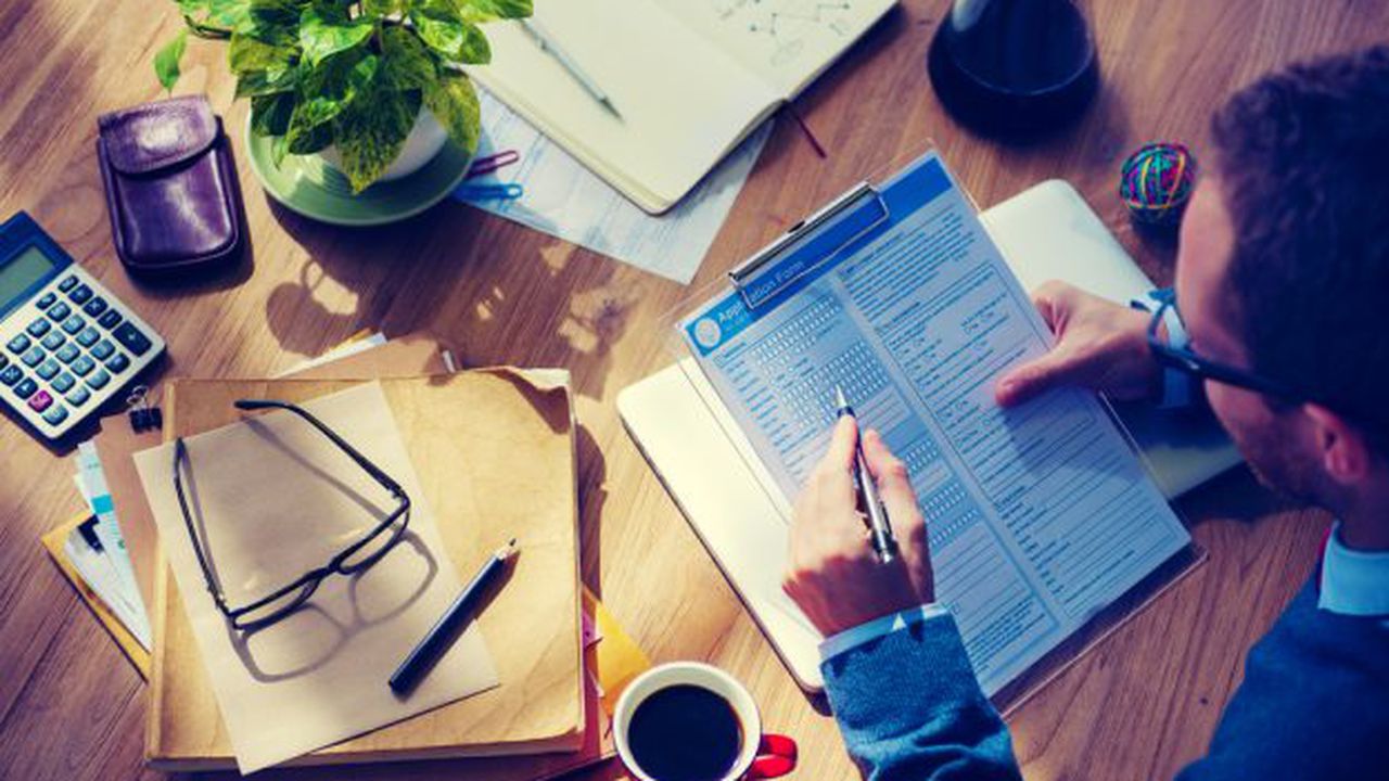 Man,Filing,Out,An,Application,On,Wooden,Table