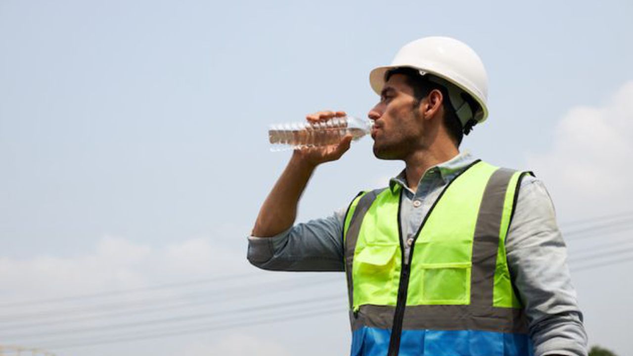 The young engineer drinks water to quench his thirst.