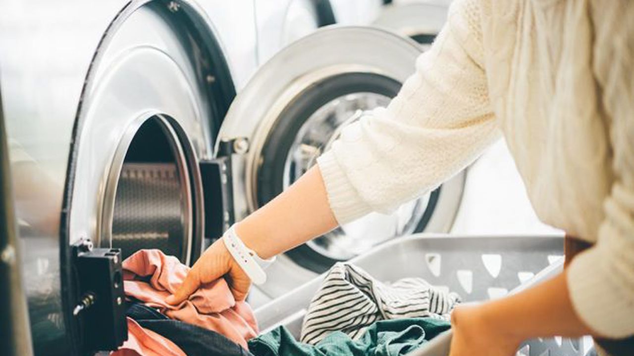 Interior of small laundromat in daylight. Close-up female holdin