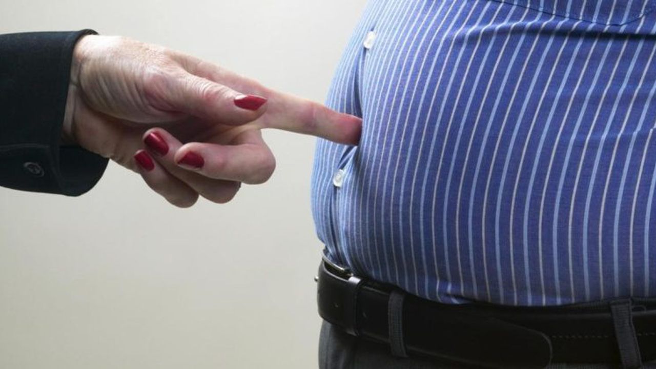 Woman poking man in stomach, mid section