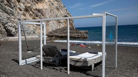 Panouri din plexiglas între şezlonguri, una dintre măsurile anti-COVID-19 implementată pe o plajă din Santorini